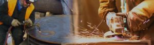 Manufacturing worker grinds steel beam while other work uses welding torch to work in a safe manner